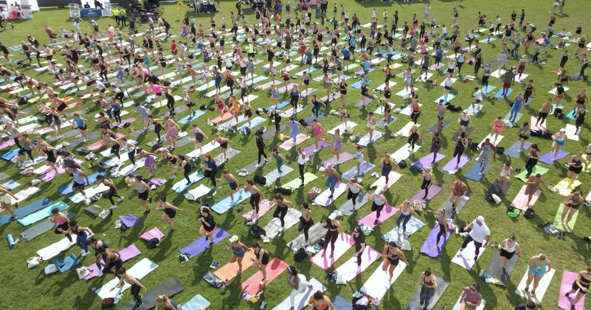 Hundreds of people doing an outdoor workout on a lawn